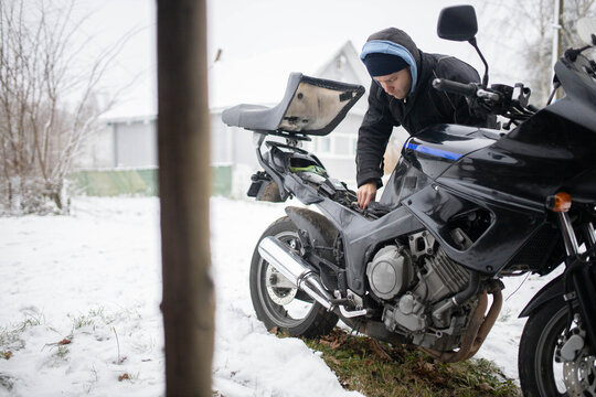 A man maintains a motorcycle in winter, motorcycle repair and maintenance