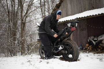 A man maintains a motorcycle in winter, motorcycle repair and maintenance
