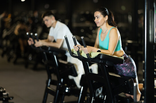 Fit woman in sportswear using standing leg curl machine at gym to strengthen hamstrings and improve lower body fitness