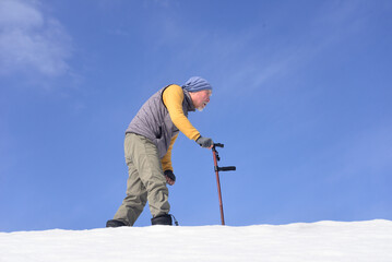 雪国で田舎暮らしの老人が杖を使ってリハビリをしている