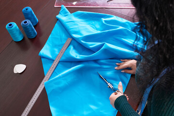 Obraz premium Dressmaker cutting blue fabric in tailor studio, atelier shop