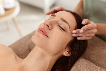 Naklejka premium Beautiful woman receiving facial massage on couch indoors, closeup