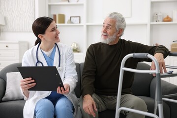 Obraz premium Care worker with clipboard talking to senior man indoors