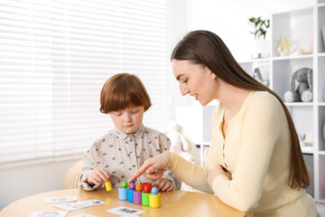 Obraz premium Mother and her son playing with toys on wooden table indoors