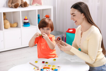 Naklejka premium Mother and her son playing with toys on white table indoors