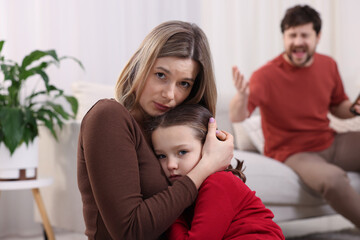 Fototapeta premium Alcohol addiction. Drunk man abusing his wife and daughter at home, selective focus