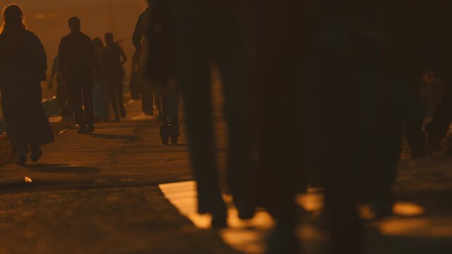 Anonymous crowd of people walking at sunset
