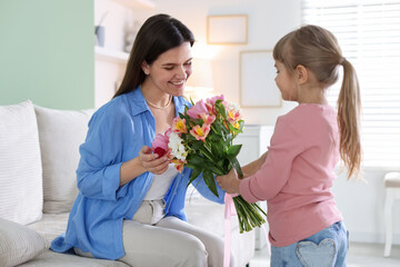 Happy Mother's Day. Little girl greeting her mom with bouquet of beautiful flowers at home