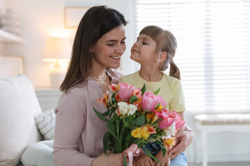 Happy Mother's Day. Mom and her daughter with bouquet of beautiful flowers at home