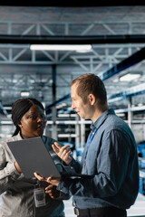 Server room coworkers troubleshooting server connectivity issues using software on notebook....