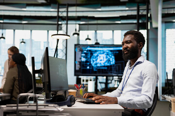 Fototapeta premium System administrator writing code, developing machine learning APIs. African american man in office troubleshooting application errors using artificial intelligence tech on green screen computer