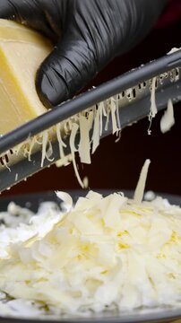Culinary expert skillfully assembles cheese mound. Experienced cook meticulously stacks shredded parmesan to create elegant culinary display