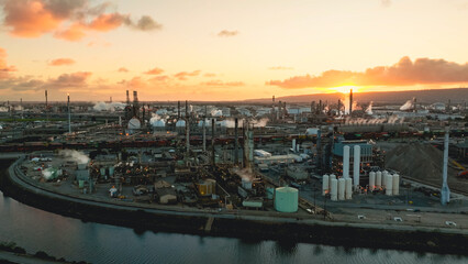 Fototapeta premium Aerial view of a sprawling oil refinery at sunset showcasing distillation towers and storage tanks