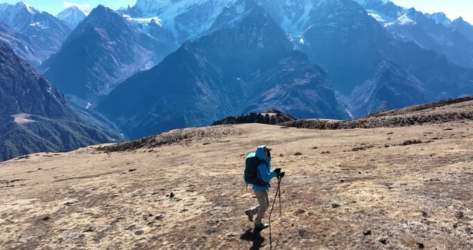 Aerial footage of backpacking woman hiking on high altitude mountain top, slow motion