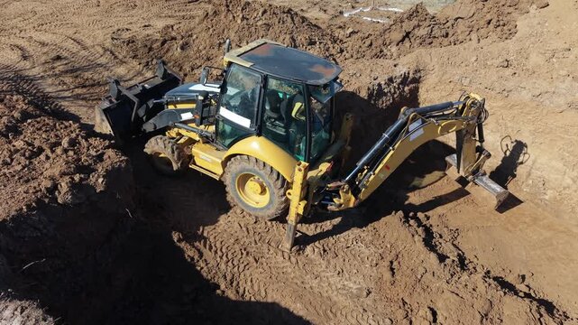 Excavator digging soil inside deep construction pit during foundation excavation. Heavy construction machinery performing earthmoving work at building site.