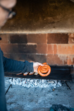Man grilling spiral sausage on outdoor barbecue