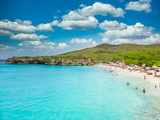 Obraz premium Aerial view of tourists enjoying the Grote Knip beach in Curacao turquoise water, palm trees, beach umbrellas 