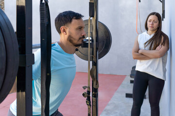 Determined athlete lifting weights while personal trainer supervises