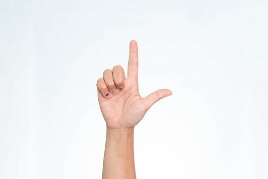 Close up of a human hand showing an L shaped finger gesture, commonly representing the letter L or a loser sign, on a white background.

