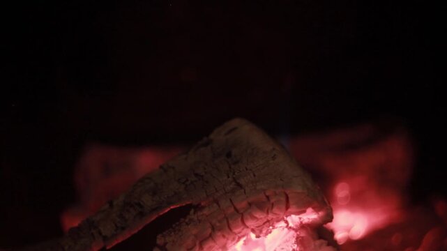 Glowing ember log burning in fireplace - cozy warm fire macro texture