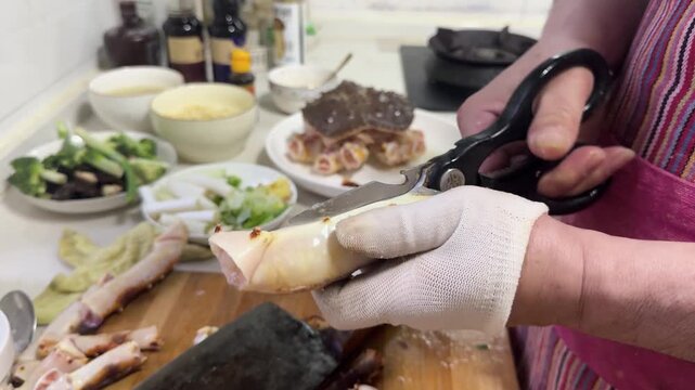 Preparing a live Shanghai hairy crab at home, with a cook cutting the crab using a large cleaver on a wooden cutting board to remove the meat from the hard shell before steaming in a kitchen setting.