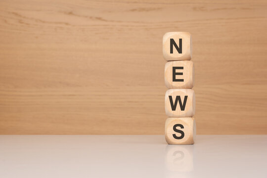 NEWS word on wooden blocks stacked vertically on a desk. Concept of journalism, mass media, global information, press release and breaking news on a wooden background.