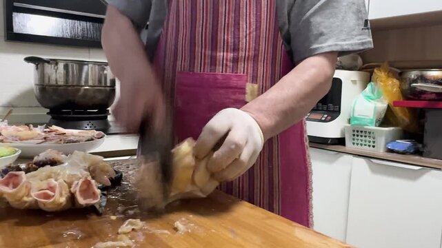 Preparing a live Shanghai hairy crab at home, with a cook cutting the crab using a large cleaver on a wooden cutting board to remove the meat from the hard shell before steaming in a kitchen setting.
