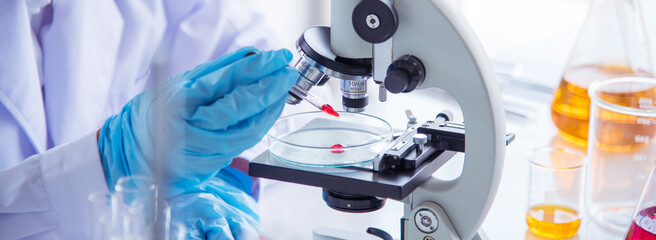 Banner Asian woman scientist hand write note research in medical lab look at science microscope. Asian Female technician laboratory using microscope with copy space. Banner Scientist chemistry
