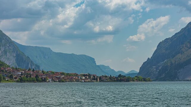 Time lapse, dancing clouds above small town near lake. Lake Como, Abbadia Lariana, Lombardy, Italy.