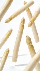 Fresh white asparagus spears falling and isolated on a clean white background