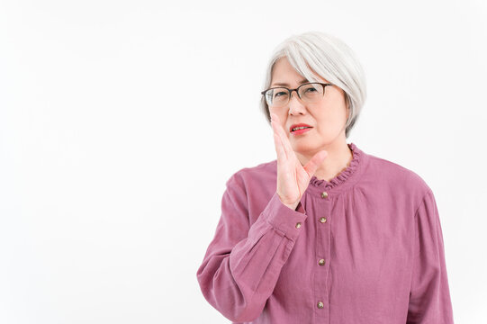 A senior woman with gray and silver hair whispering gossip, badmouthing, complaints, and nasty comments
