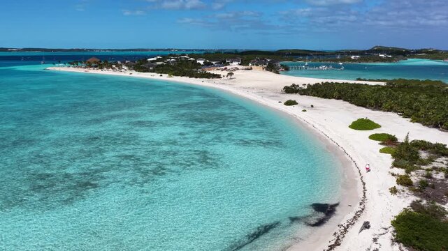Aerial view of Stocking Island in Elizabeth Harbour with a woman walking along the shoreline and the Baymahni Resort in the distance in the Exumas, Bahamas.
