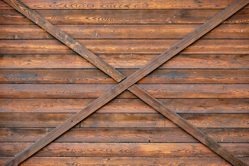 Rustic brown wood paneling creating an X pattern on a barn door texture © Довидович Михаил