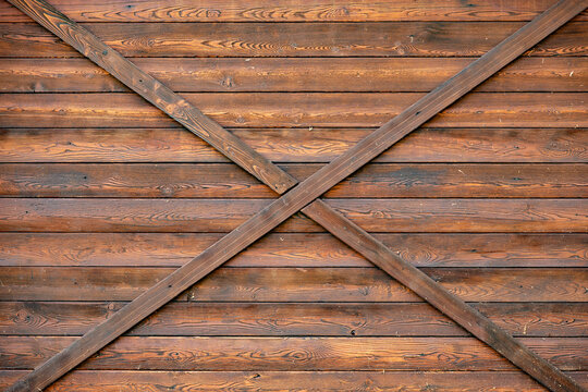 Rustic brown wood paneling creating an X pattern on a barn door texture