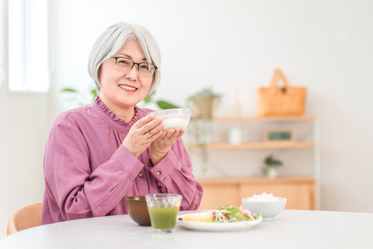 A gray-haired senior woman eating yogurt and dairy products for breakfast (bifidobacteria, lactic acid bacteria, dairy products, intestinal health)