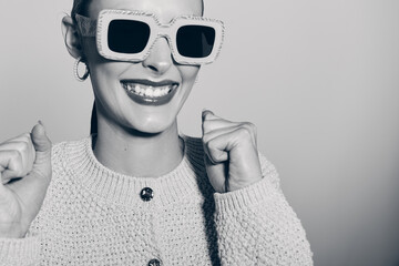 Smiling caucasian woman with light skin wearing oversized sunglasses and knitted sweater poses...