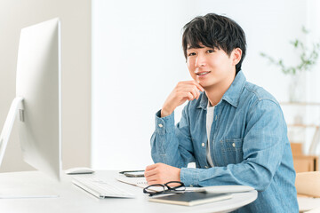 Naklejka premium A man using a computer at home to telework, online seminar, side job, video editing
