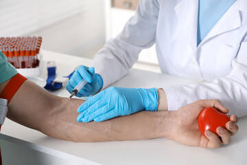 Obraz premium Doctor drawing man's blood sample in clinic, closeup