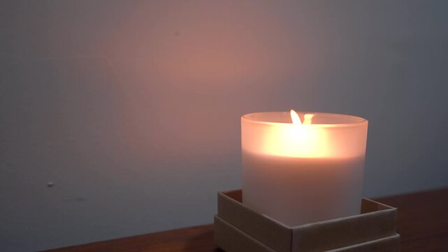Close up of a lighter lighting a candle in a glass jar against