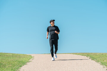 A man running/jogging under a blue sky (athlete, aerobic exercise, workout, fitness)