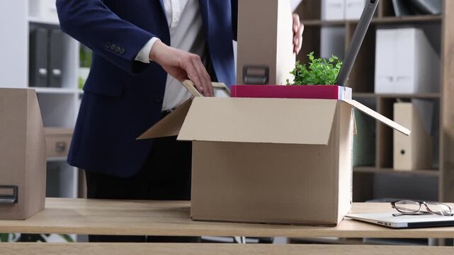 Dismissal. Man packing his personal belongings into cardboard box at wooden table in office, closeup