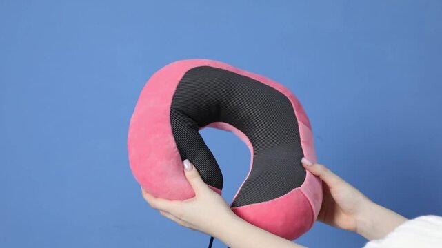 Antistress. Woman showing pink neck pillow on blue background, closeup. Space for text