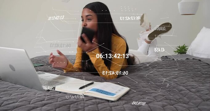 Woman on bed using laptop answering incoming call while taking work notes with timestamp overlay