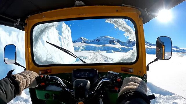 Driving a yellow snowcat through snowy mountains on a clear sunny day from the driver's viewpoint in a video