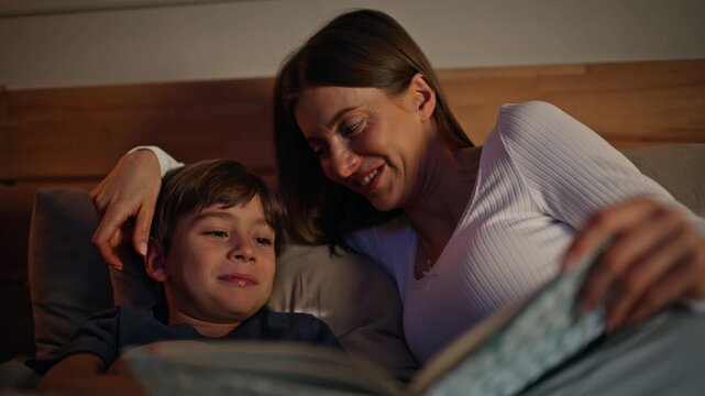 Happy mother reading son before sleeping closeup. Bonding mom smiling boy 