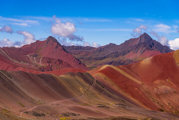Naklejka premium Rainbow Mountain trek Vinicunca seven colors siete colores montañas Peru Perú morning blue skies clouds fog movement Red Valley Peruvian Andes Mountains rainy dry season nature landscape