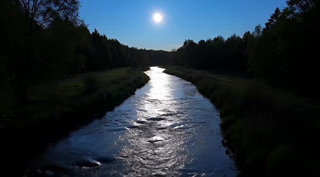 Scenic river reflecting the sun amidst a lush forest and blue sky