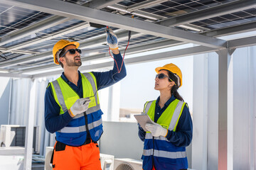 Engineers using multimeter and tablet to test photovoltaic system wiring, Technicians performing...