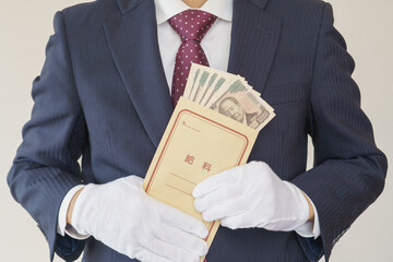 給料袋を持つスーツを着た男性｜日本の一万円札の入った給料袋