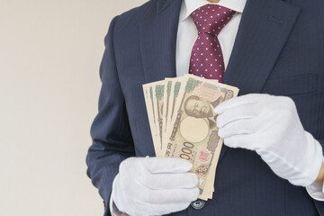 白手袋をはめて現金を数えるスーツ姿の男性